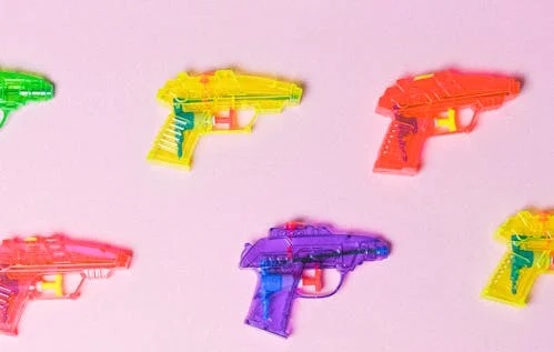 squirt guns on a pink background